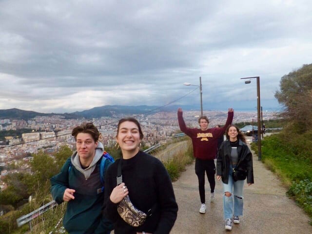 Four college students smiling and walking up to Bunkers del Carmen in Barcelona, Spain