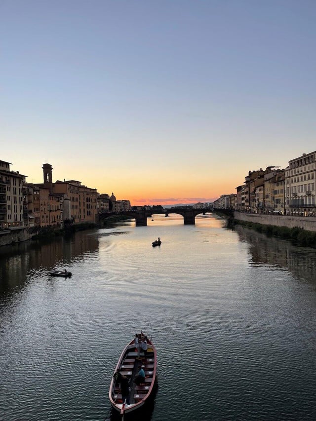 Gondola on the Arno River and Ponte Vecchio during sunset in Florence