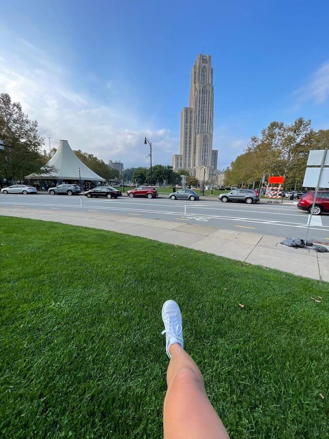 student sticking out their white shoe on the lawn on the Pitt campus