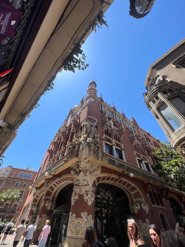 A red building in Barcelona with a sculpture on a corner pillar