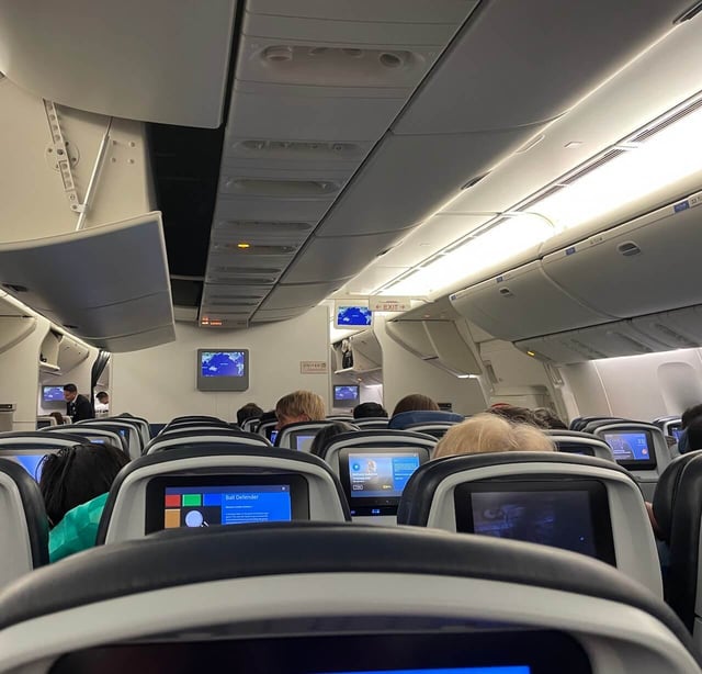 Seats and in-flight entertainment screens inside a flight cabin