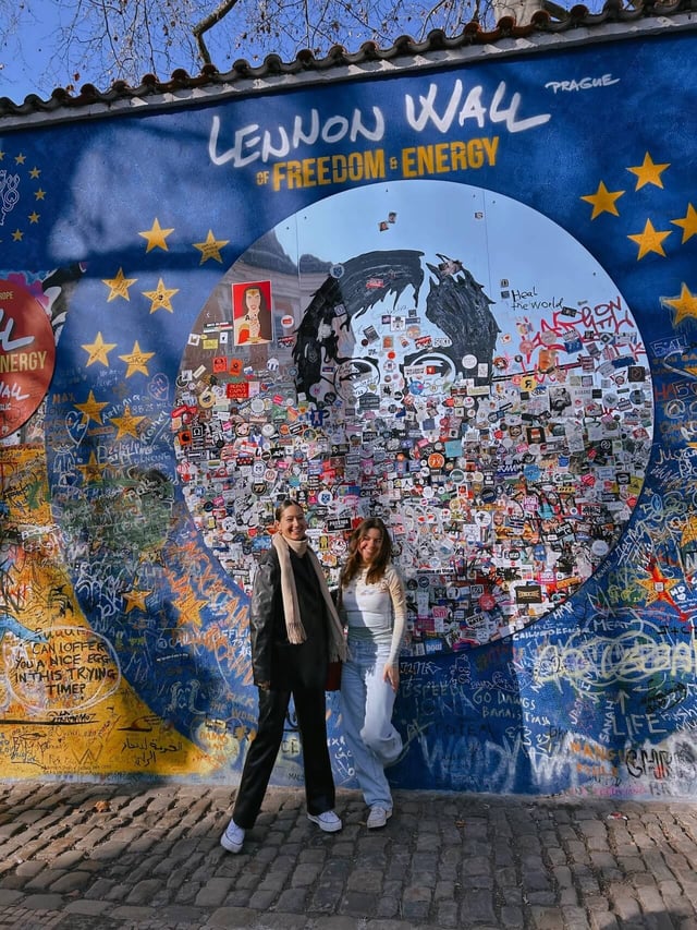 Two people standing in front of the decorated John Lennon Wall in Prague